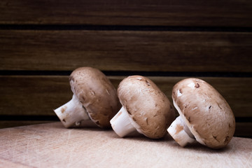 Brown champignon on cutting board and wooden background 