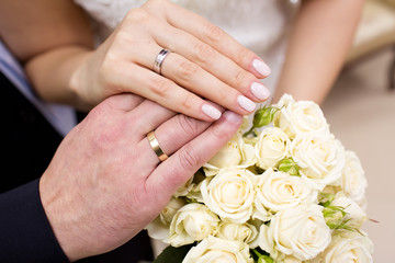 Obraz na płótnie Canvas Hands with wedding rings on bride's bouquet