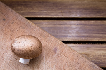 Brown champignon on cutting board and wooden background 