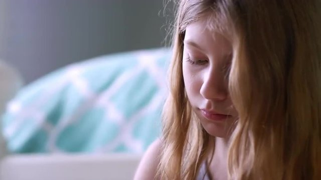 Close up on a girls face as she focuses on an art project in her room