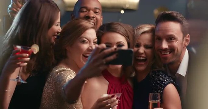 Smiling group of friends celebrate evening event with selfie at party