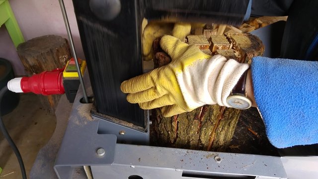 worker with wood splitter in action, hydraulic, electric, firewood