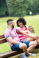 Portrait of young couple in love having a rest together on a park bench.