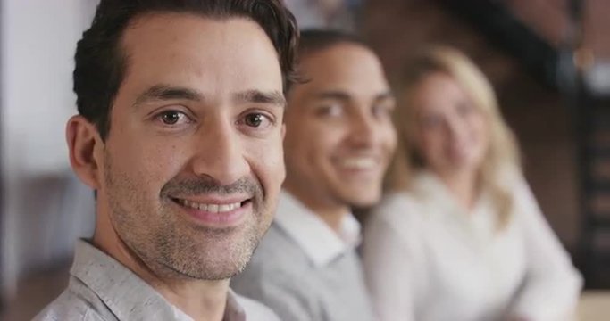 Portrait of a confident young business woman at boardroom table in trendy modern shared office space a diverse team chatting together slow motion turning around smiling