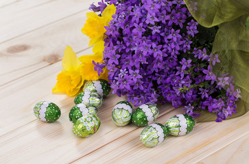 Wiosenny bukiet kwiatów z żonkilami i czekoladowe jajka na jasnym tle  © DariuszO