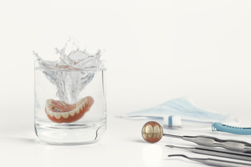 Teeth on mirror next to dentures in water