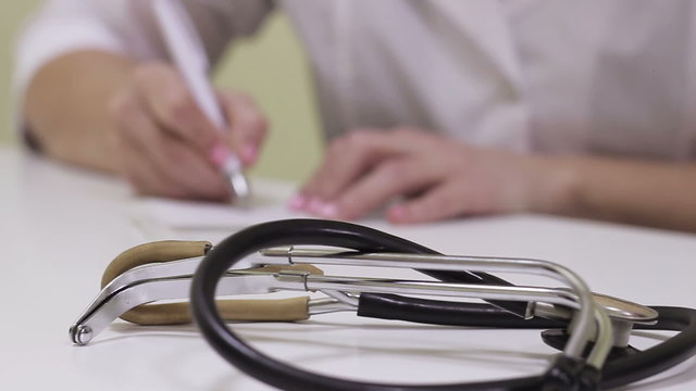 Doctor in the office records in the patient's card