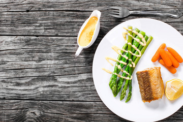 grilled hake served with asparagus, piece of lemon, baby carrots