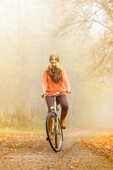 Naklejka premium Active woman riding bike in autumn park.