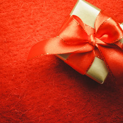 Small golden box with gift tied red bow