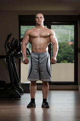 Fototapeta na wymiar Young Man Flexing Muscles In The Gym