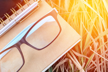 Notebook glasses pen and smart phone on the grass.