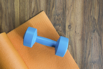 dumbbell and yoga mat on wood table