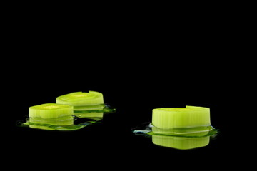 drei stücke lauch mit wasser auf schwarzen hintergrund