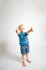 Young blonde boy giving the thumbs up sign.