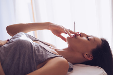 Fototapeta premium Smoking girl lying by the window