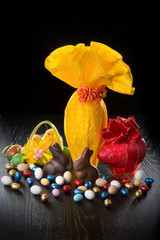 Uova di pasqua con coniglietti e ovetti colorati di cioccolato e pulcini nel cestino su sfondo nero