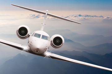 Airplane fly over clouds and Alps mountain on sunset. Front view of a big passenger or cargo...