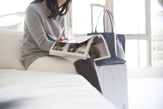 Women are reading a magazine sitting on the bed