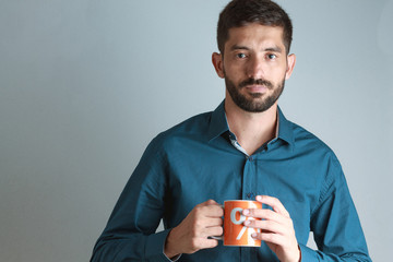 Young business man wearing blue shirt, drinking coffee / tea in