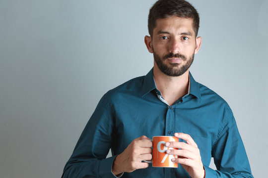 Young business man wearing blue shirt, drinking coffee / tea in
