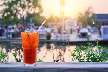 Iced lemon tea with sliced lemon and summer party background near lake.