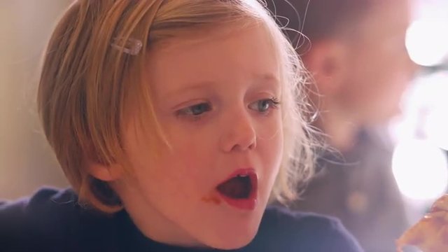 Close Up Of A Cute Little Girl Taking A Big Bite Of Pizza At Home