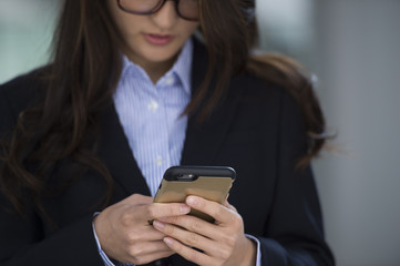 Young woman wearing a suit is looking at smartphone