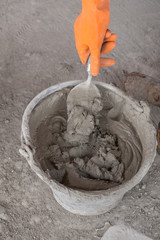 hand with trowel and bucket with mortar at consturction site