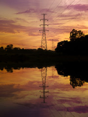Silhouette of high voltage post with water reflection