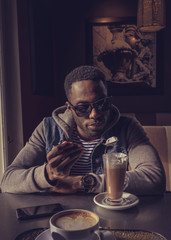 Blackman in sunglasses drinking coffee.