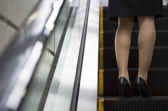 Feet of the women who are riding on the escalator
