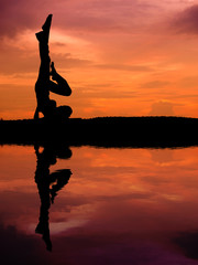 Silhouette of a beautiful Yoga woman with water reflection