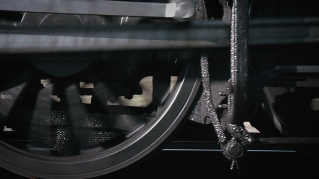 Close-up of steam train wheels moving fast along a track.