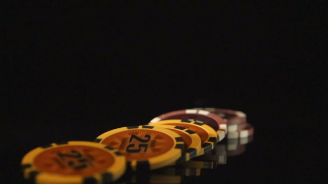 SLOW: A playing chips falls on a black desk
