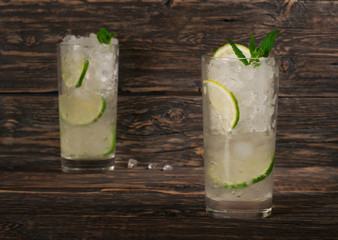 Cocktail with rum in tall glass with ice, lime, mint