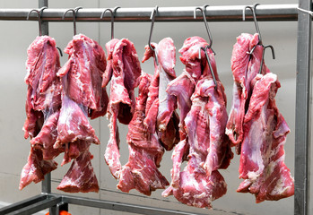 Fresh red meat hanging on metal hooks