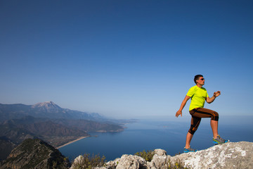 Man practicing trail running with a coastal landscape in the background.