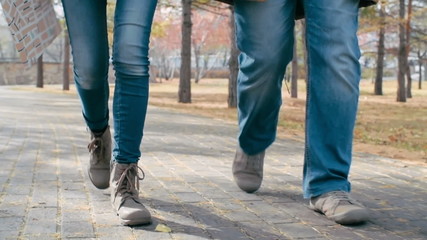 Close up of legs of man and woman walking towards the camera in the park - Powered by Adobe