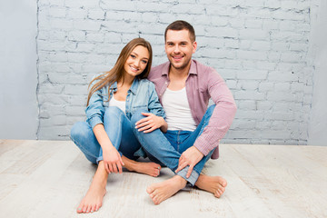 Happy pretty man and woman sitting barefoot on the floor
