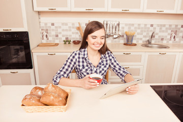 Cheerful young woman drinking coffee with cakes and reading news