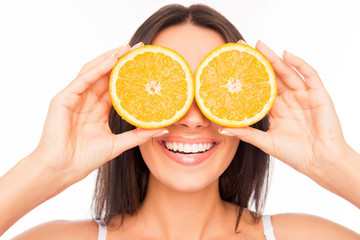 Close up of cheerful woman holding two halves of orange near eye