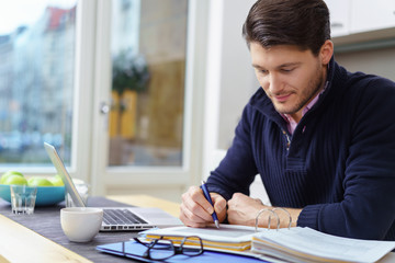 student arbeitet zuhause mit unterlagen und notebook