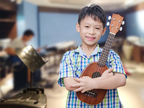 Asian boy with ukulele at music school