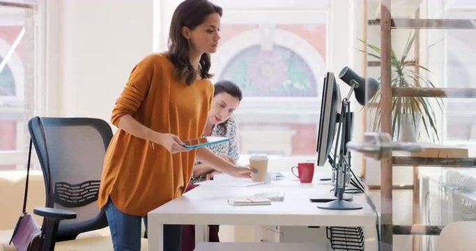 Mixed race team of young business people working in open plan office desk rows of computers in shared workspace bright natural light