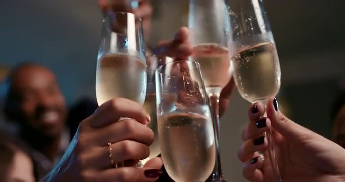 Friends holding up champagne flutes together in a toast at party