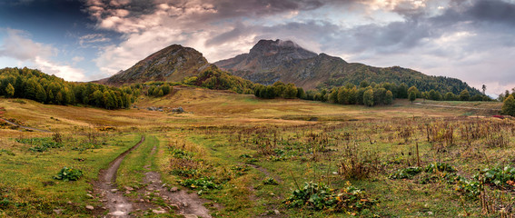 Ridge in Krasnaya Polyana, Sochi area in autumn and the dirt road at the foot of the mountain - Powered by Adobe