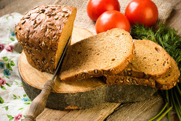 Fresh bread slice and cutting knife on rustic table