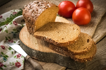 Fresh bread slice and cutting knife on rustic table