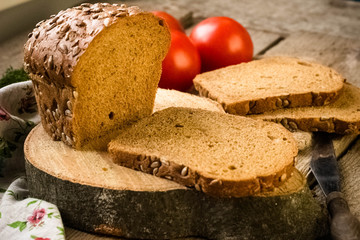 Fresh bread slice and cutting knife on rustic table